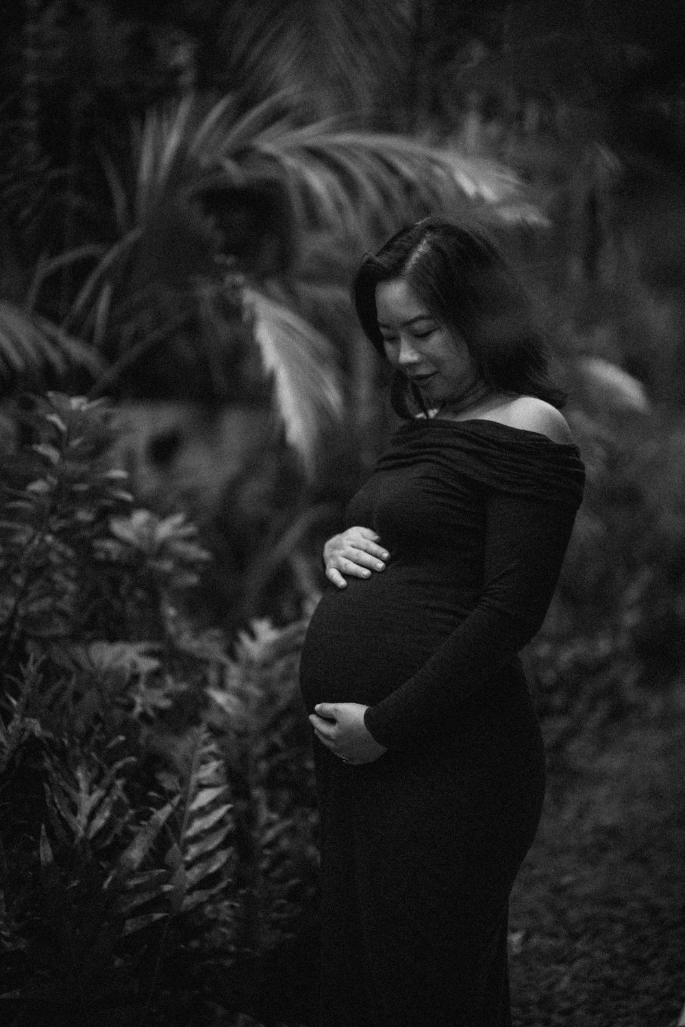 Atmospheric black and white portrait among tropical foliage.