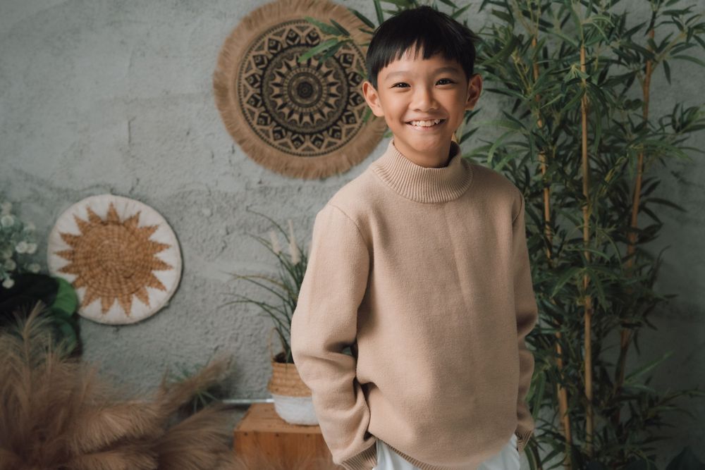 Person in beige sweater sitting against wall with decorative circular wall art.
