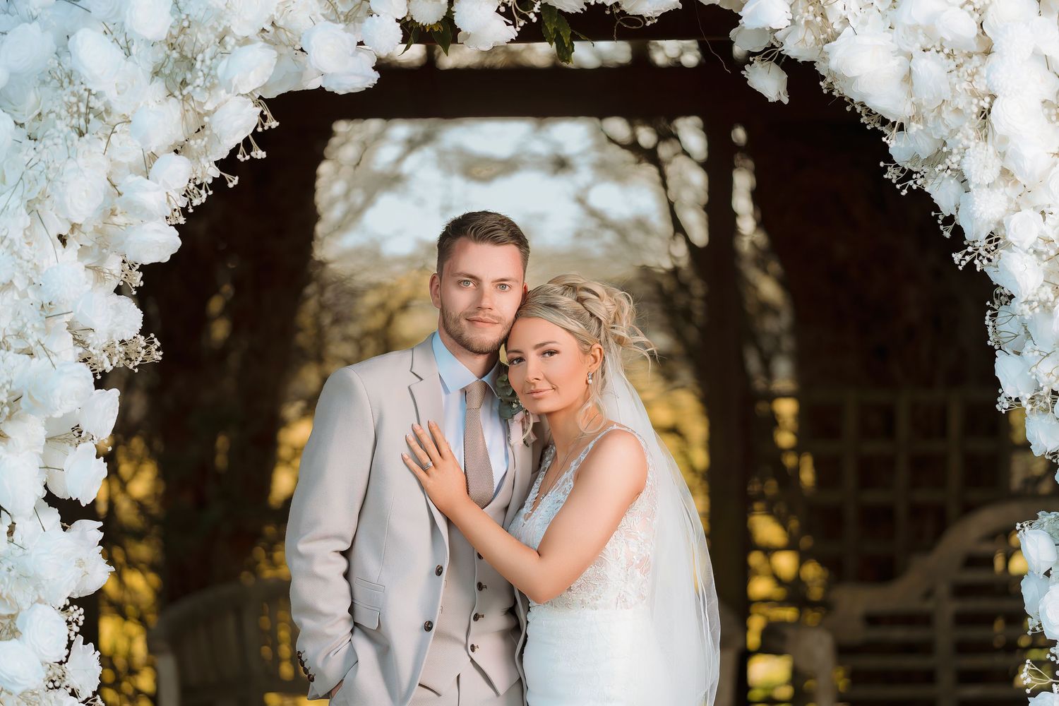 A bride and groom share romantic moments under flowering cherry blossom trees at sunset.