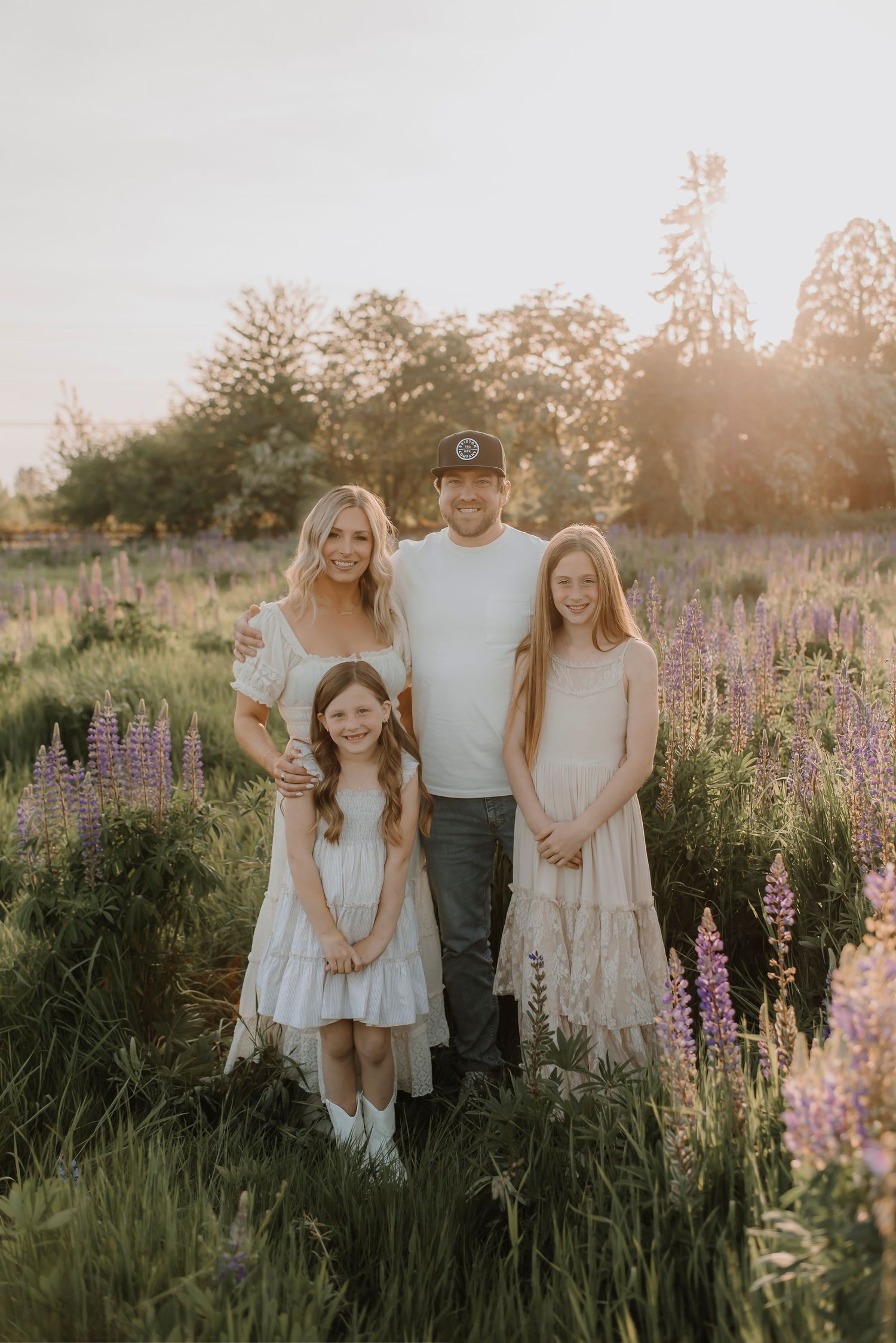 Family portrait in field of purple lupine flowers during golden hour.