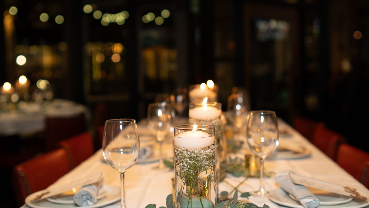 Elegant candlelit table settings at a formal dinner party with glowing ambiance and crystal glassware.
