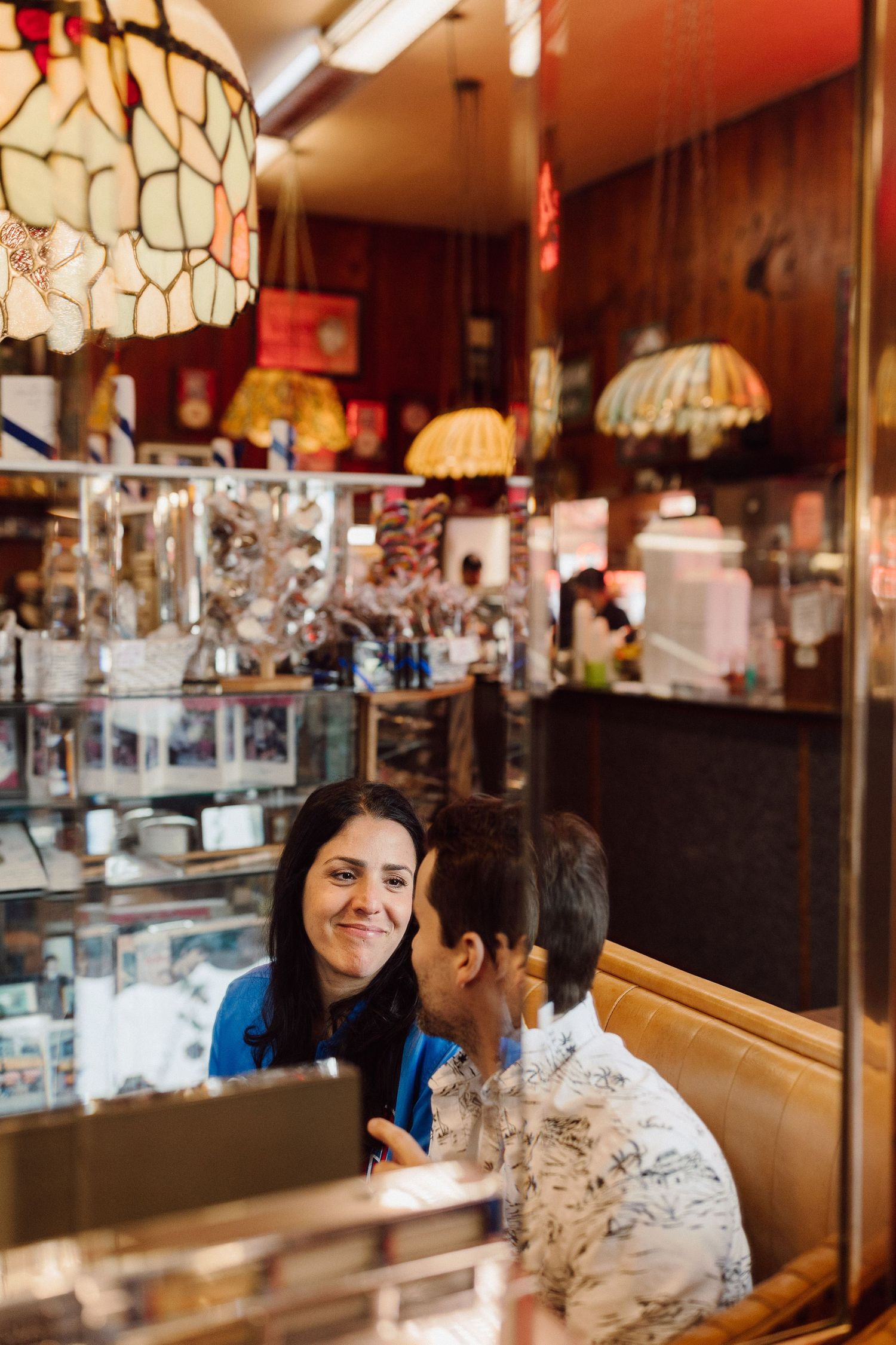 Couple sharing a sweet moment in a vintage diner booth with stained glass decor.