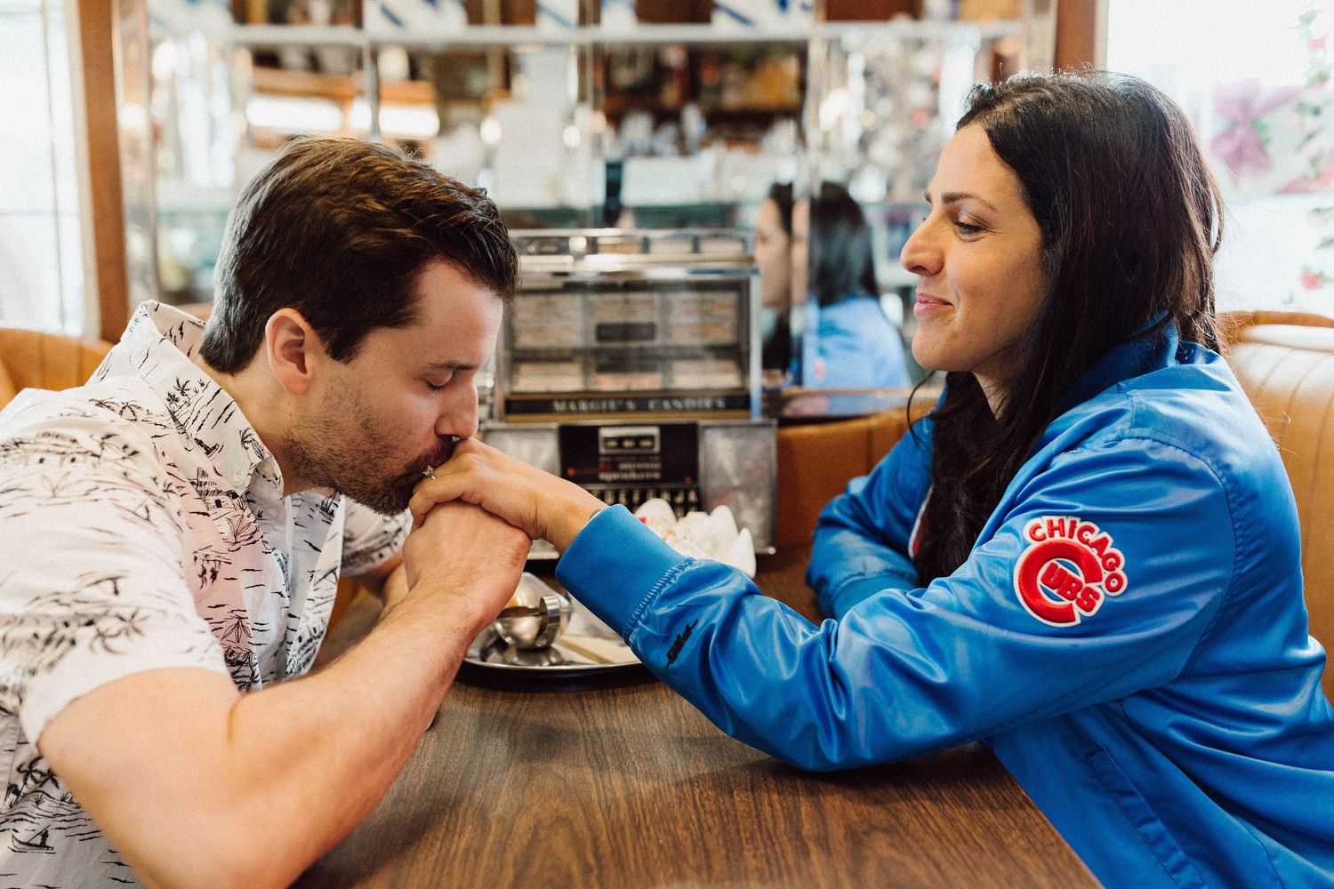 Couple sharing dessert at a restaurant booth with stained glass lighting overhead.