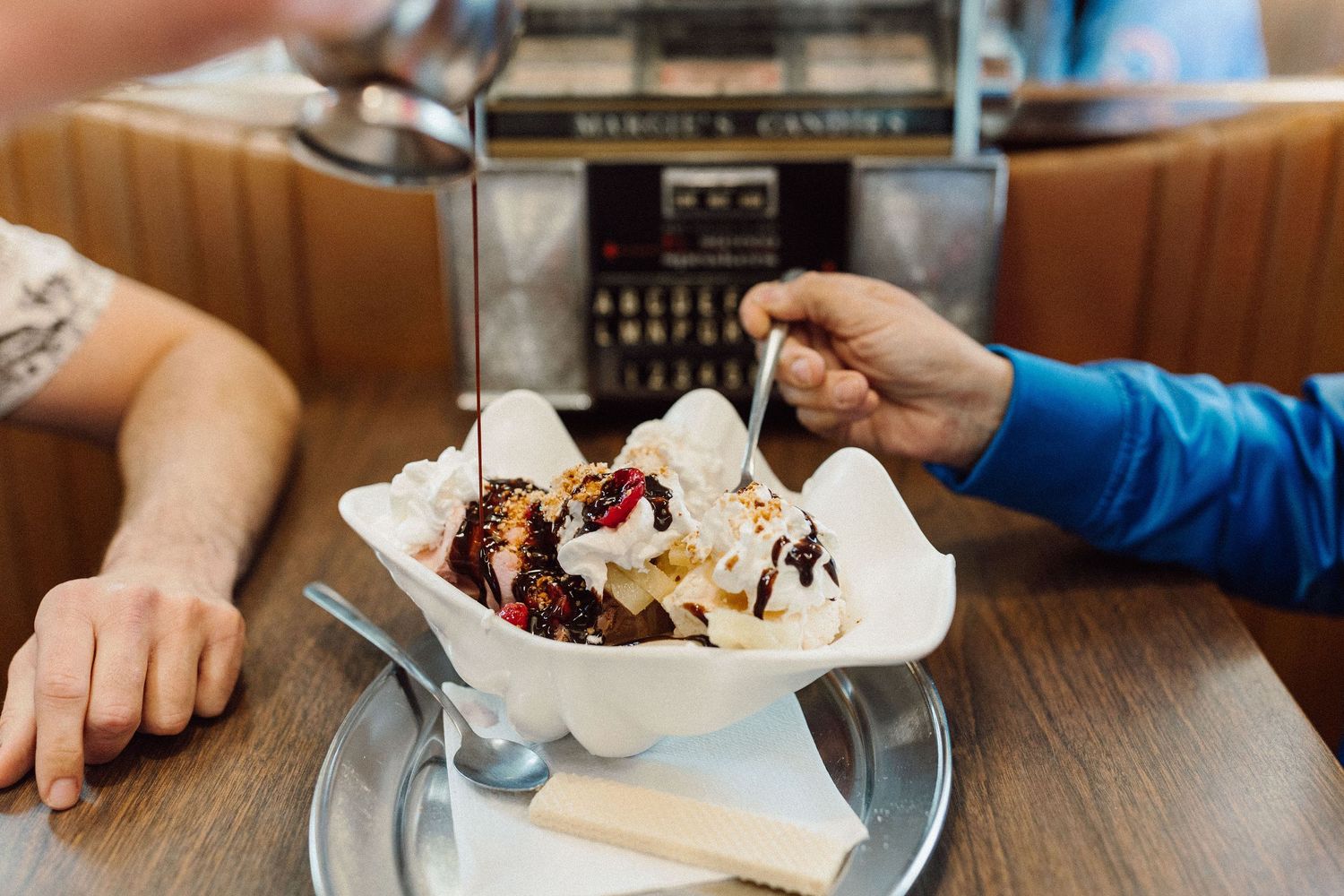 Close-up of ice cream sundae being shared with two spoons at a diner.