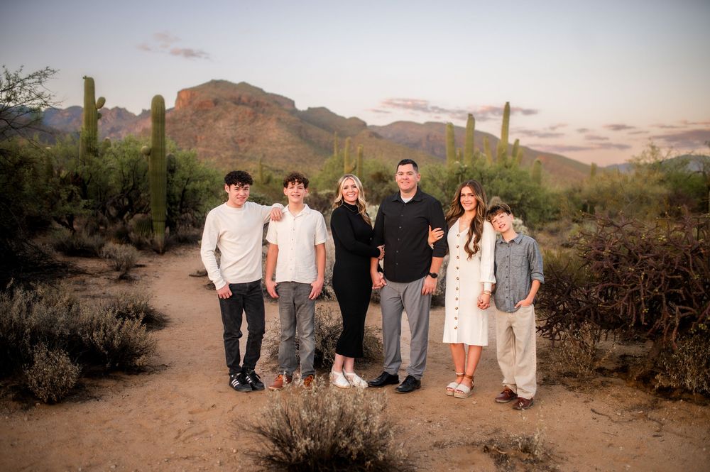 Family of six posing in Arizona desert at sunset with saguaro cacti and Superstition Mountains backdrop.