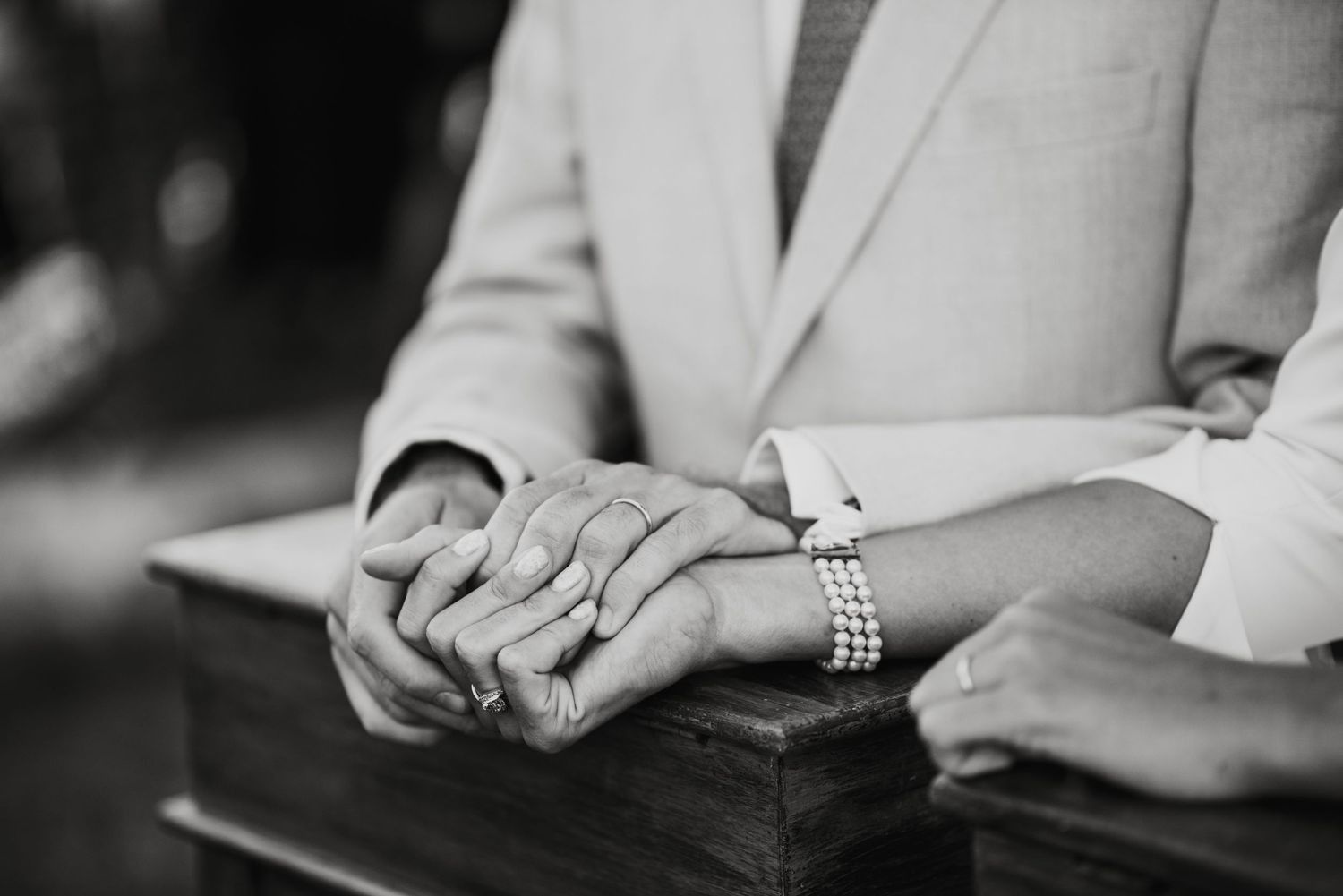 Close-up of hands with wedding rings in intimate black and white.