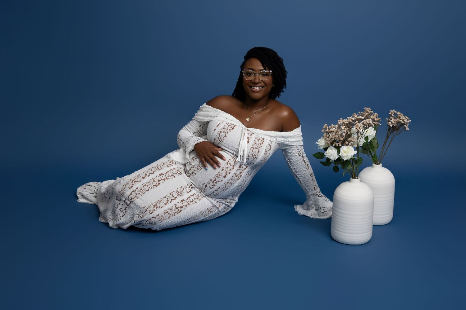 White lace wedding shoe and candles arranged on blue background in elegant bridal still life composition.