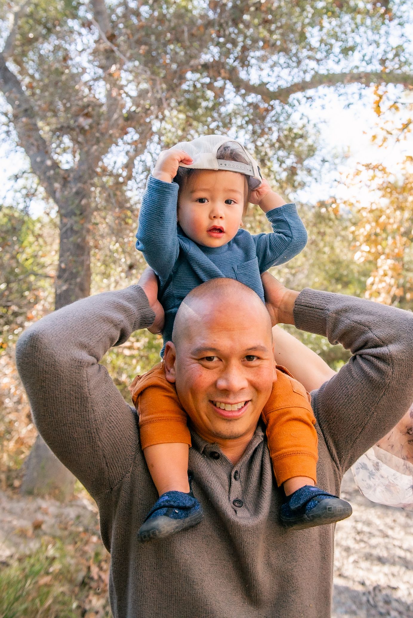 A playful sequence of four shots showing a child being lifted and carried on someone's shoulders outdoors.