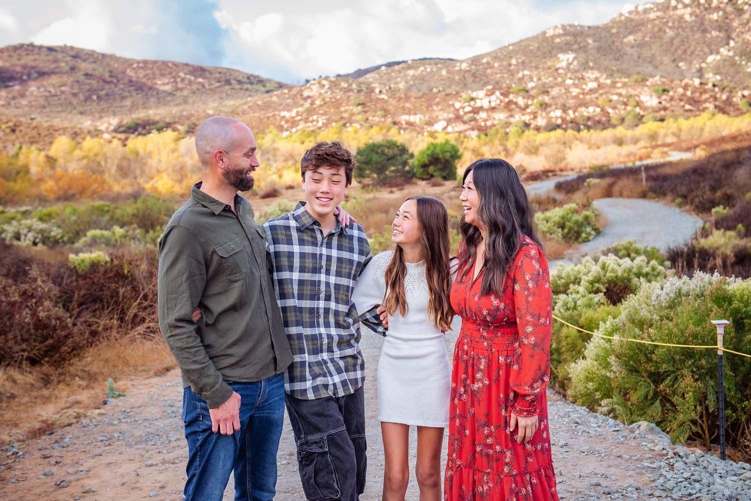 Group poses together on a scenic mountain trail during golden hour with desert landscape in background.