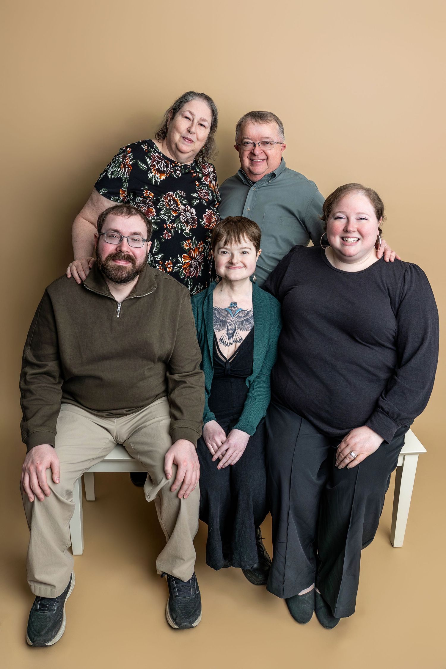 A group portrait series showing three people sitting together in casual clothing against a beige background.