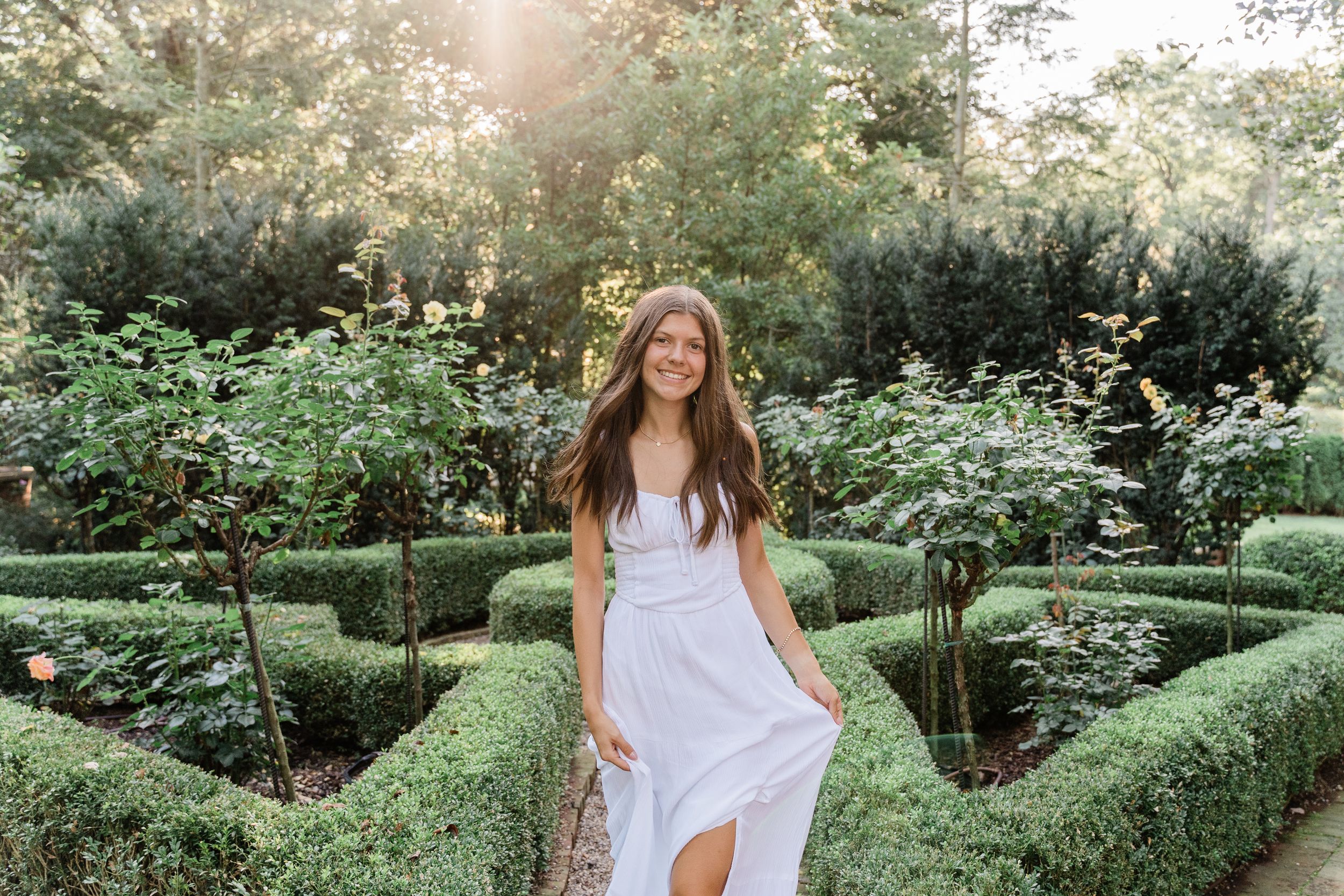 Golden sunlight illuminates a garden path with manicured hedges and natural landscaping.