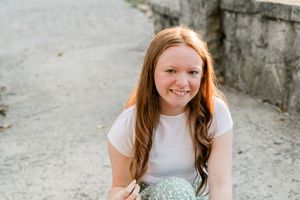 A person in a white top poses for a series of casual outdoor portraits against a stone wall.