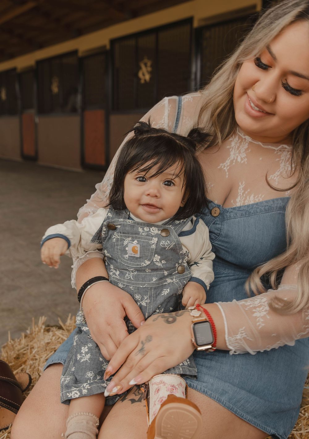 Close-up view of children playing with hay while sitting in casual denim outfits.