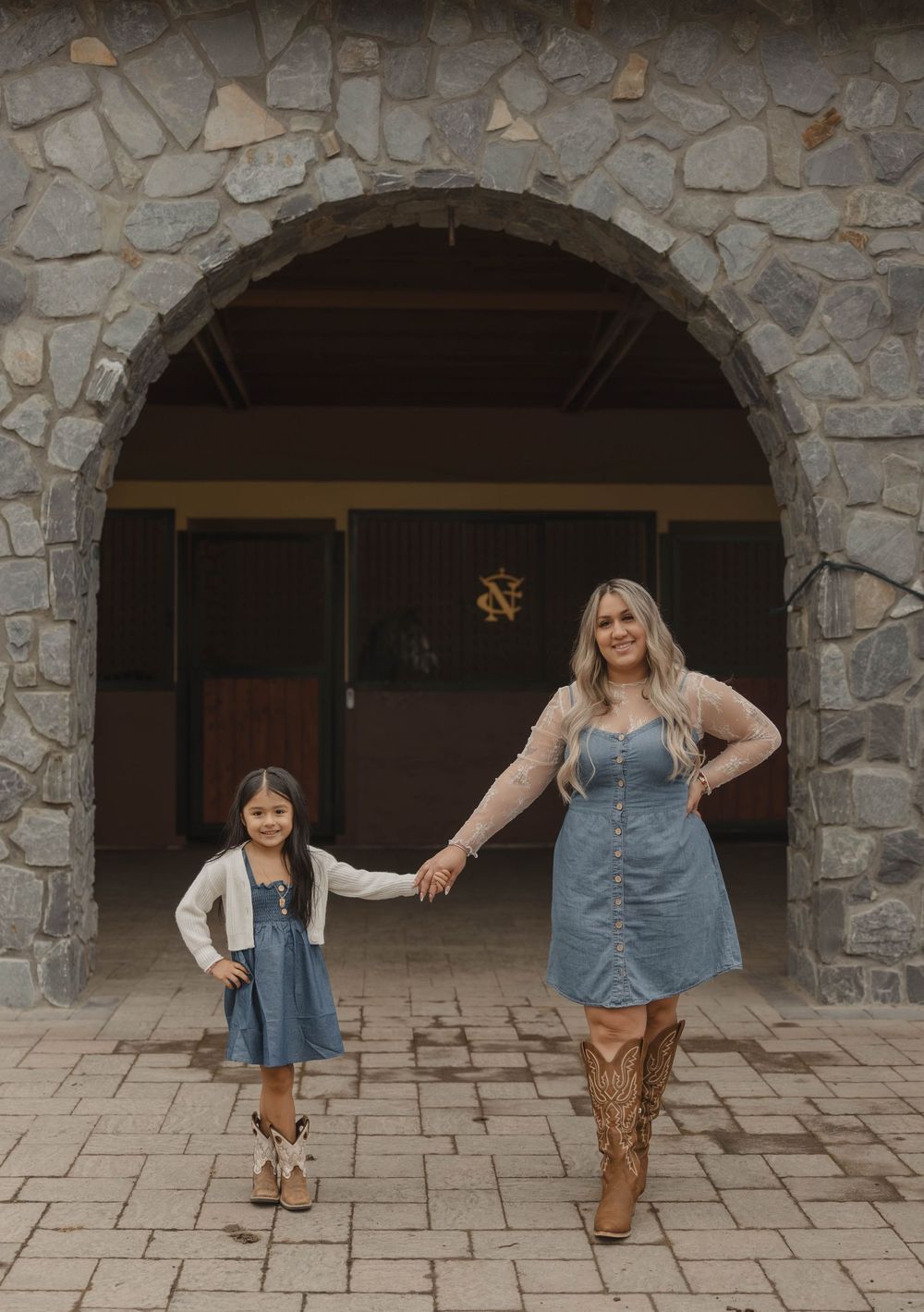 Family members in western wear pose playfully under stone archways.