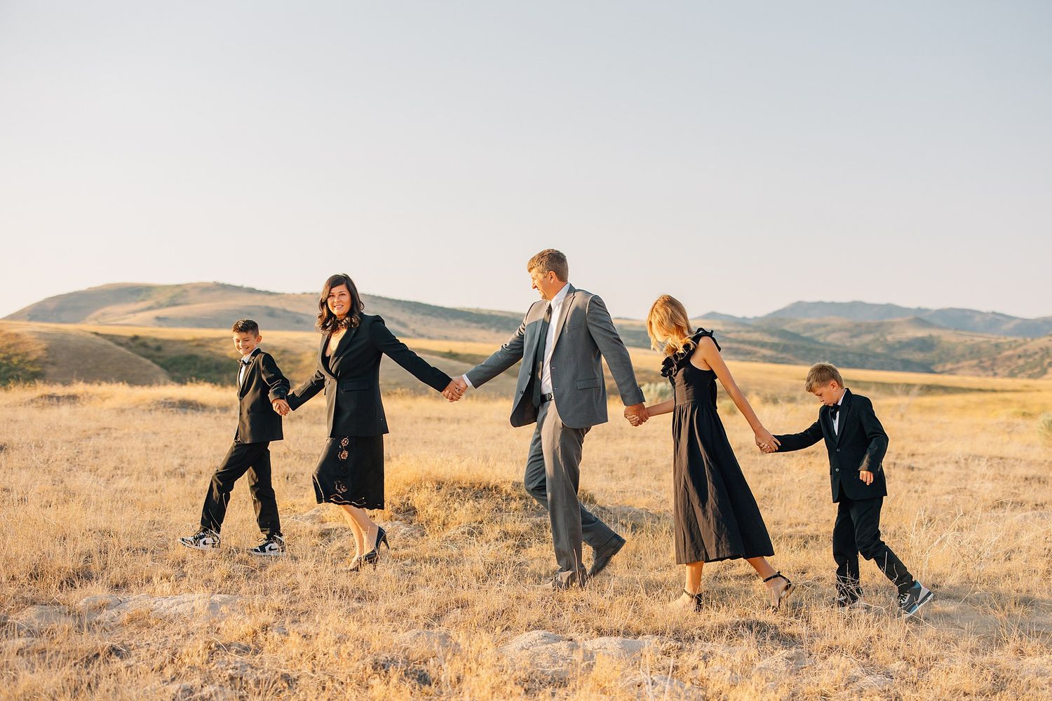 Family members run and play together across a golden autumn field at sunset in the countryside.