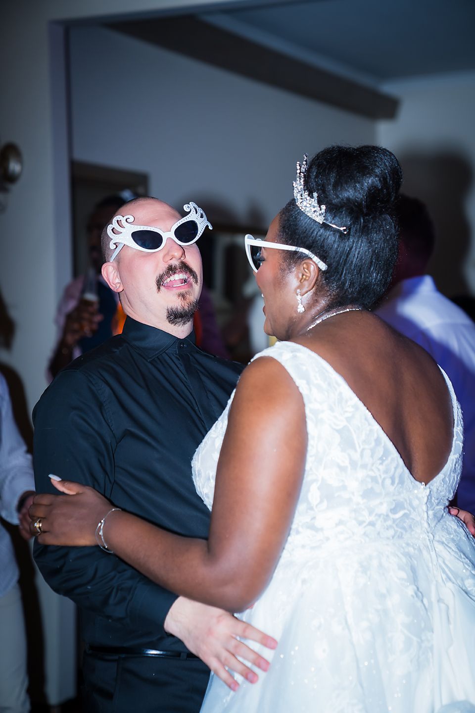 A couple dances together at a wedding reception, with the bride wearing white and her partner in black attire.