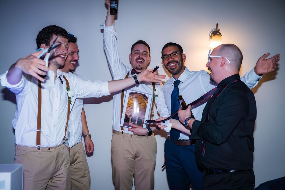Joyful wedding party members in suits dance and celebrate together during a reception.
