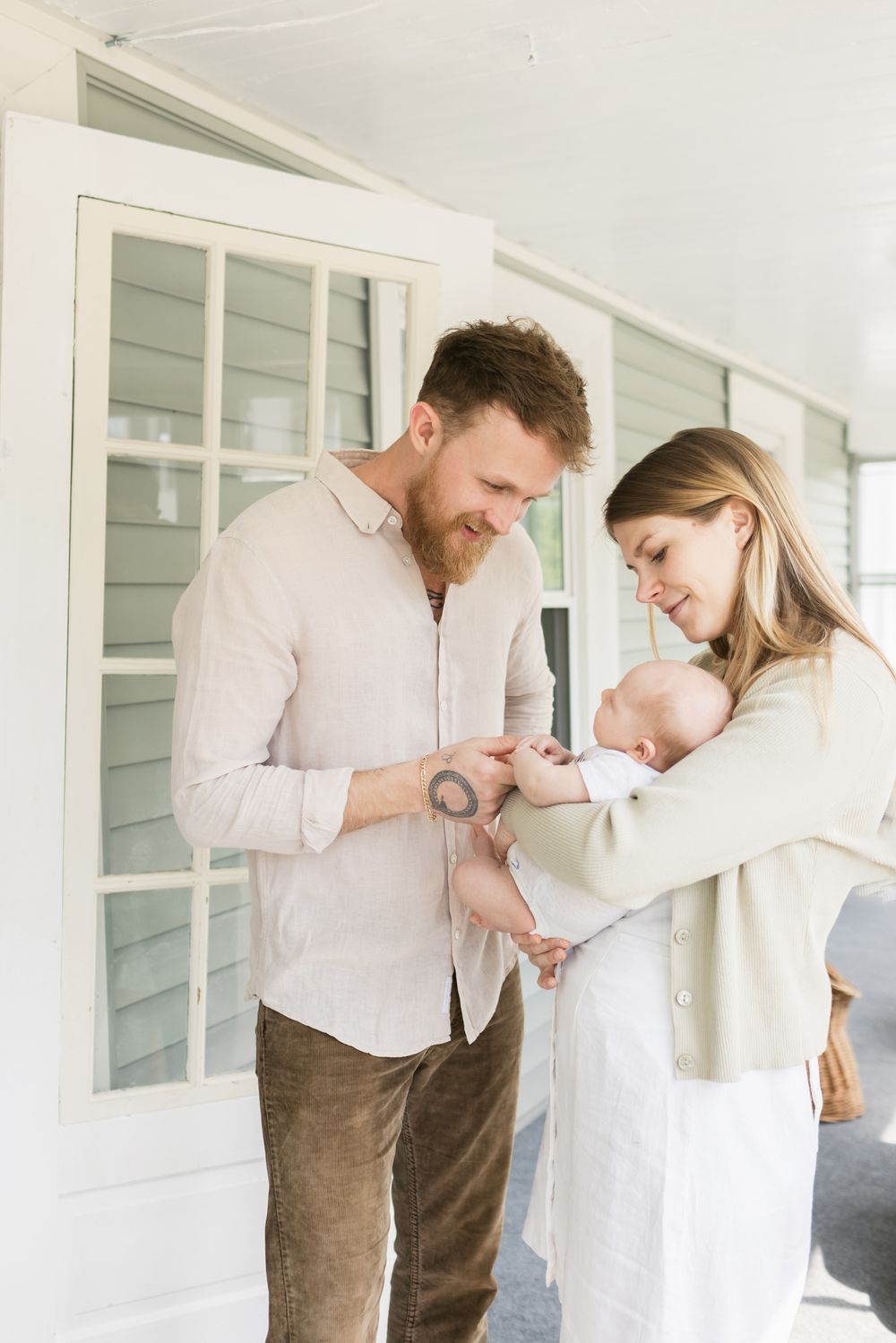 Couple enjoys their baby on their porch for newborn family photos in Berwick, Maine. Lakes Region White Mountains NH newborn photographer.