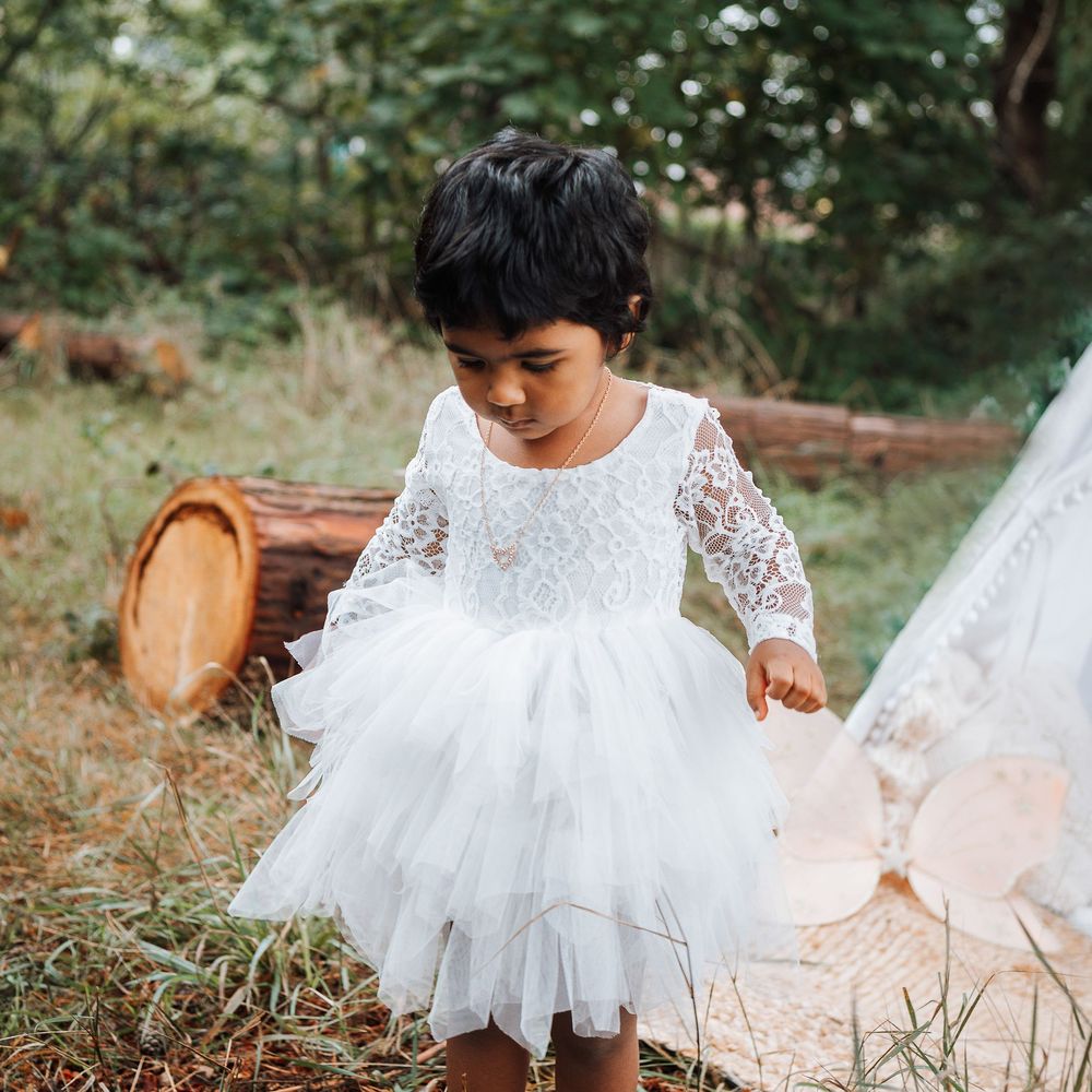 Young girl walking away from a teepee in a woodland setting.  Very natural and in a nursery garden.