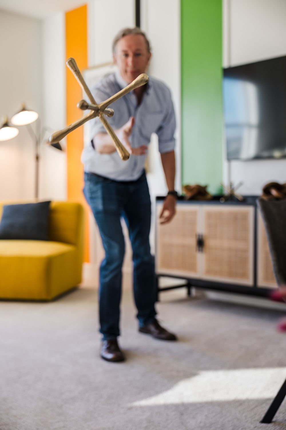 A candid lifestyle portrait of a man holding a large model airplane in a modern, sun-drenched living room.