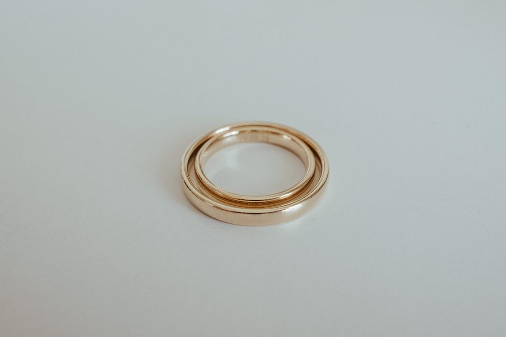 Simple rose gold wedding band ring displayed on clean white surface, elegant minimalist design.