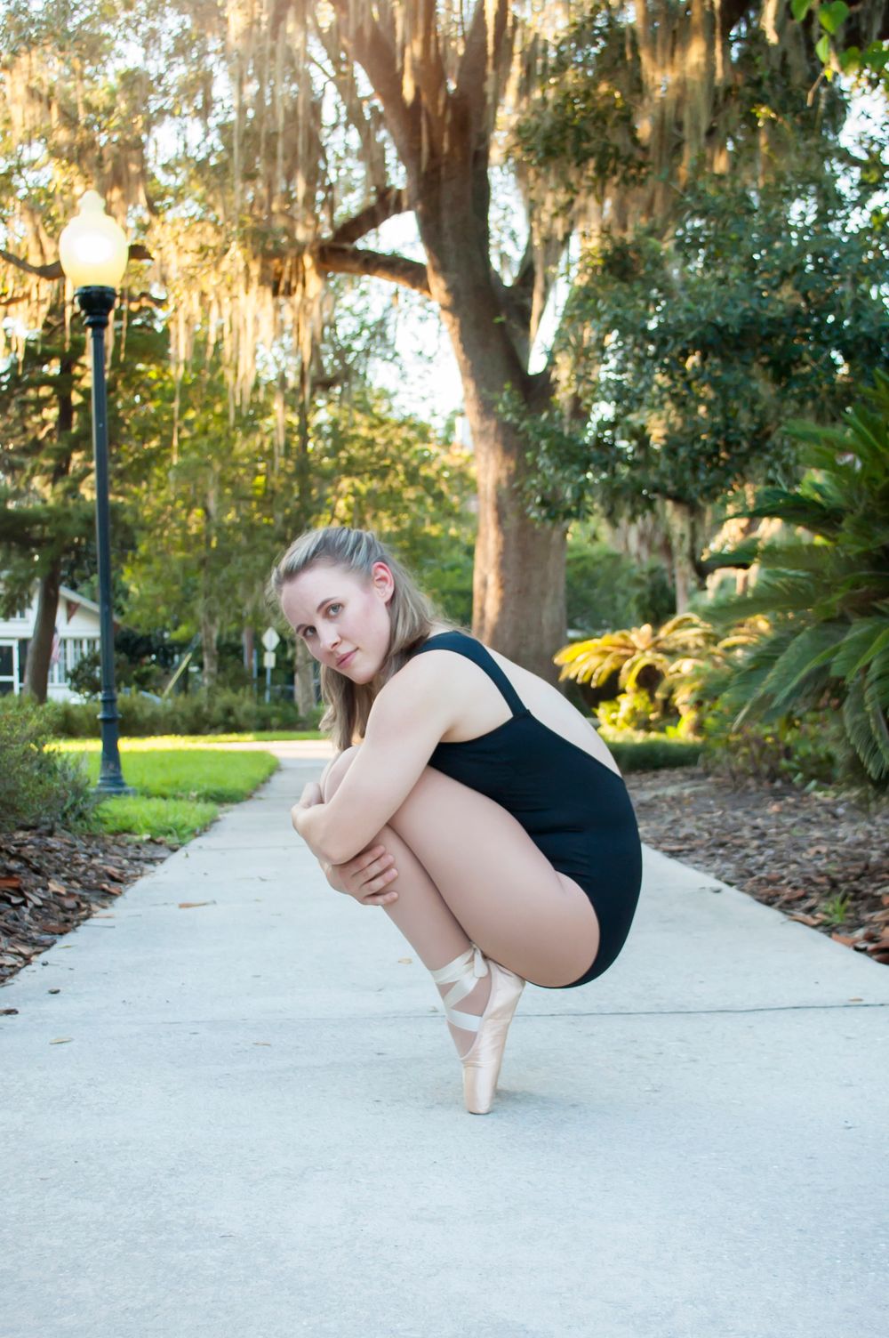 Solo female college grad session dramatic ballerina pose. Soft afternoon natural lighting in Gainesville Florida at the Thomas Center