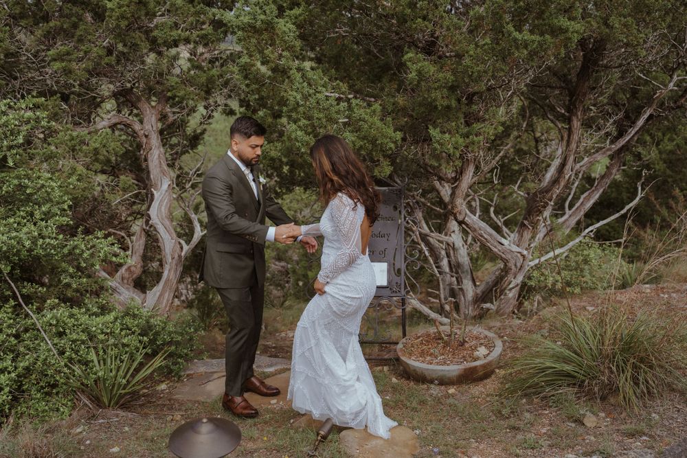 Bride and groom exchanging vows outdoors surrounded by lush green trees.