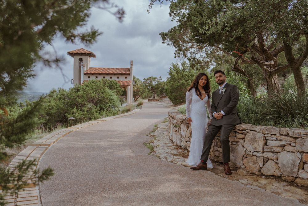 Bride and groom posing by stone wall at elegant outdoor wedding venue.