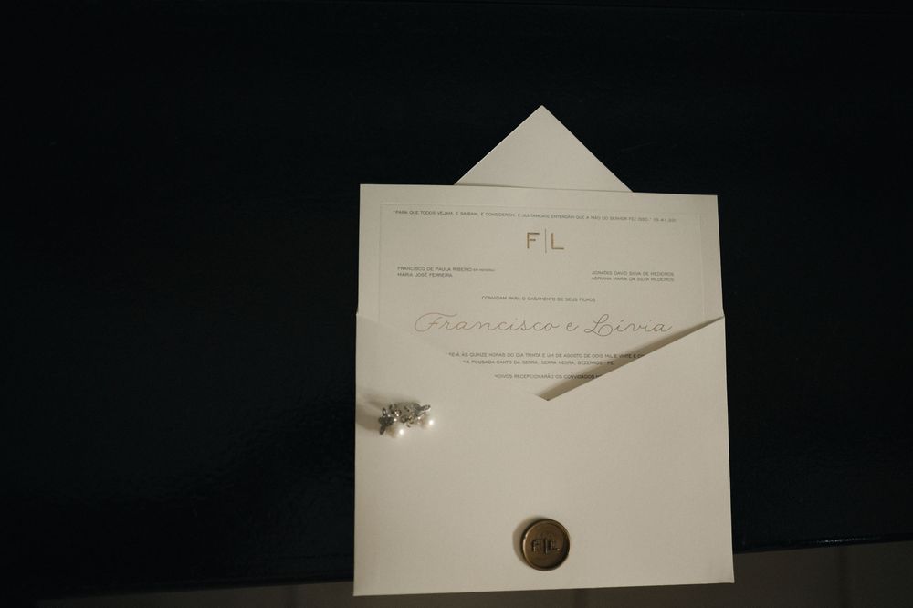 Elegant wedding invitation with wax seal, monogram, and calligraphy script on cream paper with envelope.