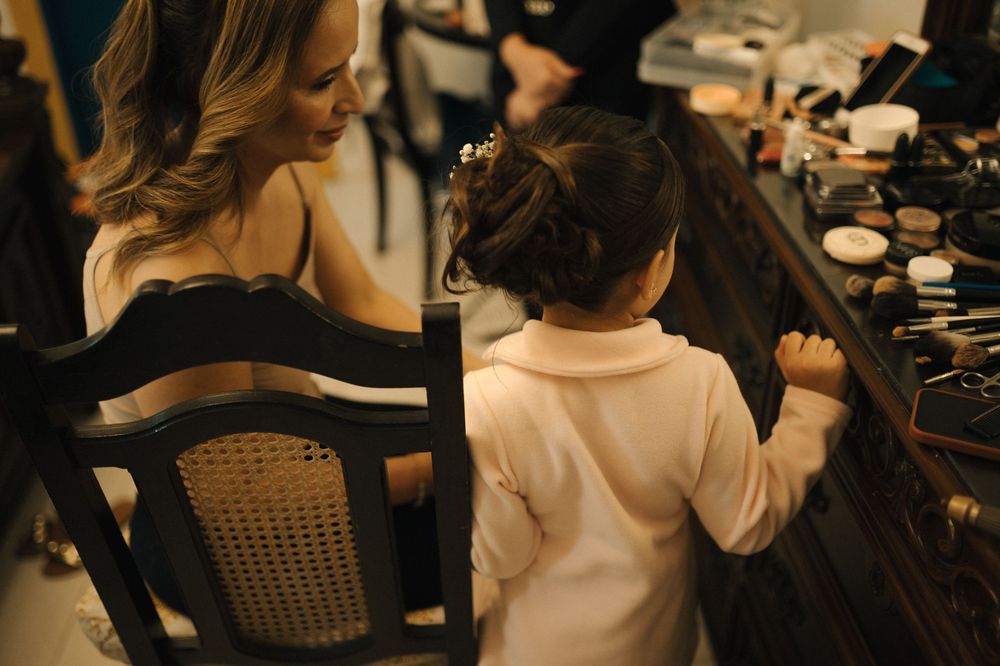 Woman and young girl explore makeup vanity together in elegant wedding preparation setting.