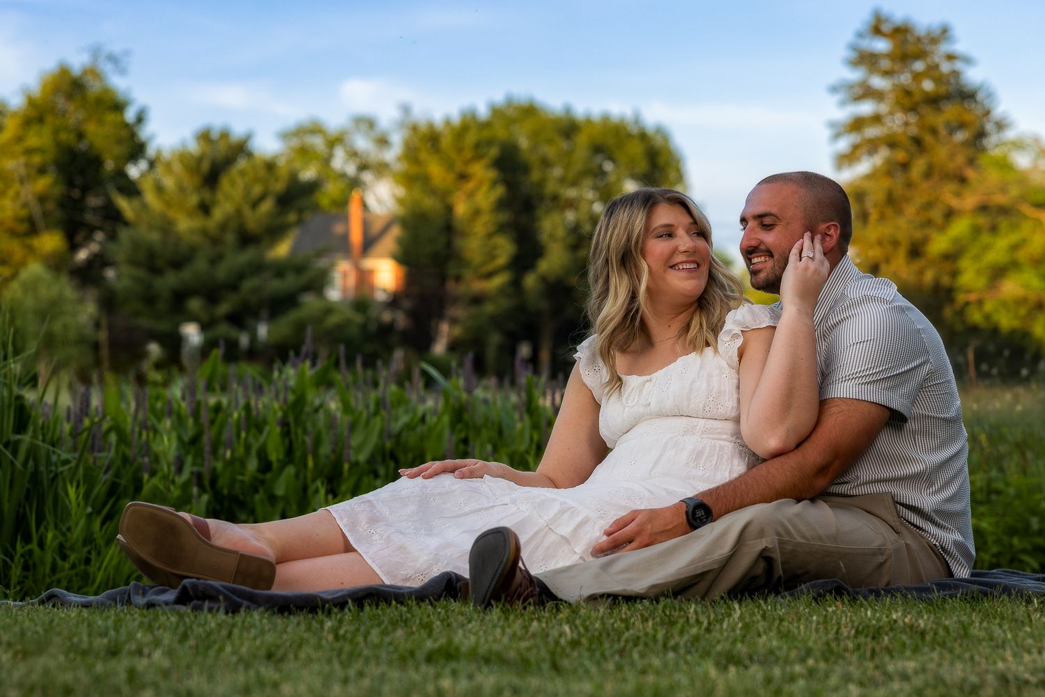 Romantic couple sharing a tender nose-to-nose moment outdoors with pink cherry blossoms in the background.