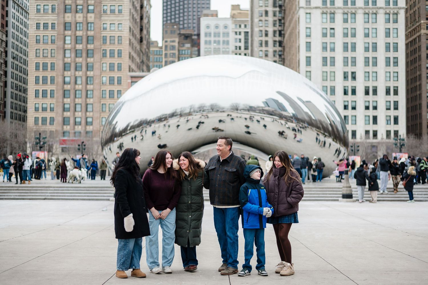 Large family group smiling together on sofas in a cozy living room with city photography wall art.