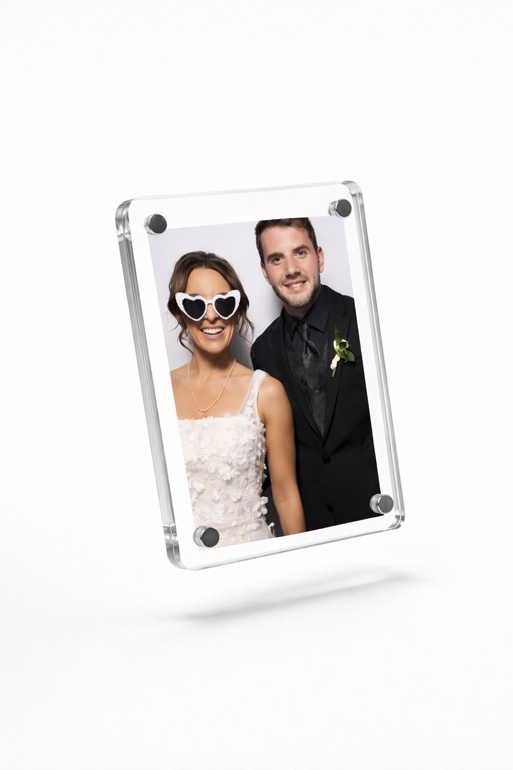 Couple in acrylic photo frame, bride in white dress with heart sunglasses, groom in black suit with boutonniere.