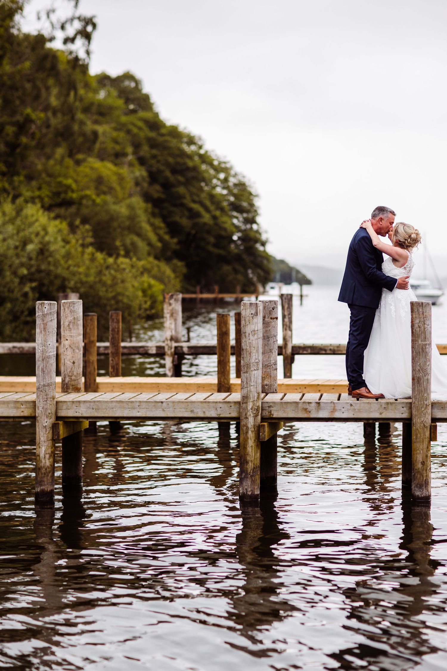 Bride and groom sharing a romantic kiss under a lush garden archway on their wedding day.