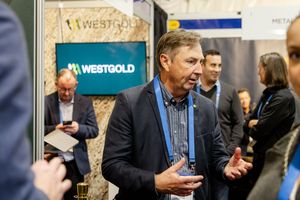 Business executive speaking at Westgold mining company exhibition booth at industry conference.