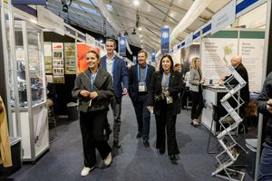 Professionals networking and walking through a busy indoor trade show exhibition hall with display booths.