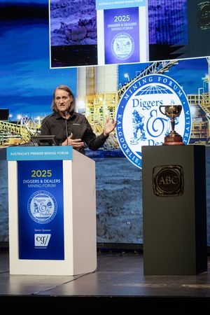 Speaker presenting at the 2025 Diggers and Dealers Mining Forum with the ABC Bullion Melbourne Cup trophy.
