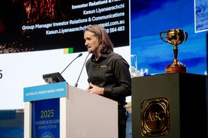 Speaker at 2025 Diggers and Dealers Mining Forum podium with Melbourne Cup trophy nearby.