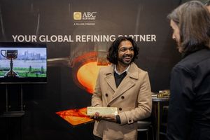 Man smiling while holding a gold bar at the ABC Refinery Global Refining Partner display booth.