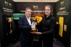 Two men holding the Melbourne Cup trophy at an ABC Refinery gold refining exhibition booth.
