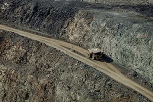 Aerial view of a large haul truck navigating a winding road in an open-cut mine.