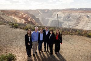 Group of six professionals posing at a large open-pit gold mine in outback Australia.