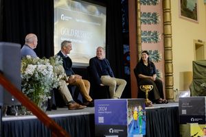 Panel discussion at Gold Business event with four speakers seated on stage with Melbourne Cup trophy.