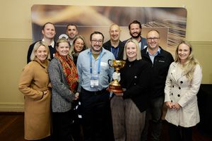 Group of professionals posing with a trophy cup at a mining industry award ceremony.