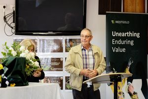 Speaker at podium beside floral arrangement at Westgold Unearthing Enduring Value branded indoor event.