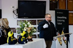Man in white gloves standing near a Westgold branded banner reading Unearthing Enduring Value.