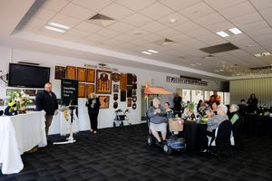 Indoor corporate event space with guests seated at tables and standing near displays at Westgold presentation.