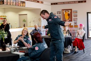 Paramedic interacting with smiling guests at a community fundraising luncheon event indoors.