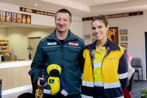 Male paramedic and female mining worker posing together holding a yellow stuffed toy bear.