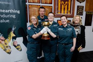 Paramedics and staff smiling while holding Lexus Melbourne Cup trophy at Westgold mining industry event.